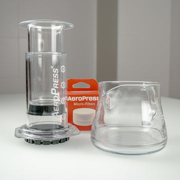 Kit AeroPress Clear con CAFEC Server y filtros sobre una mesa de café.