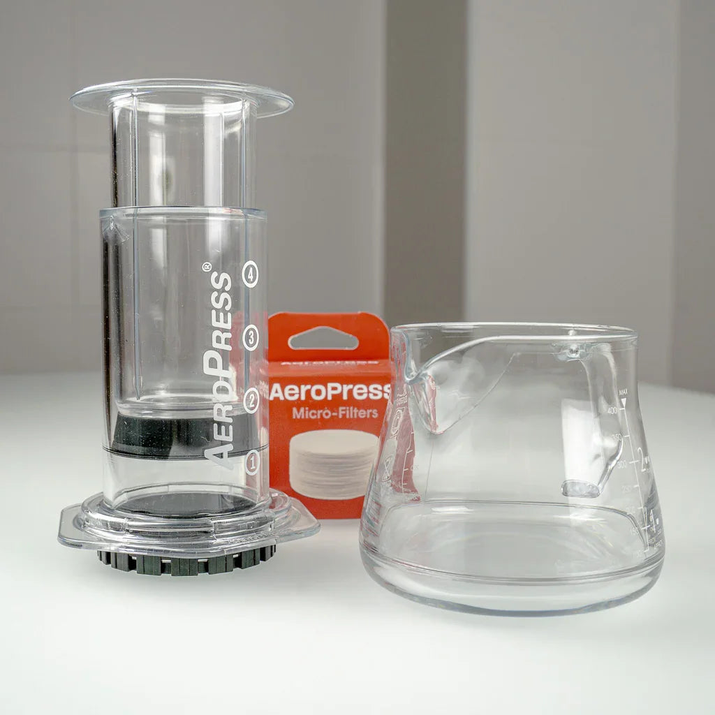 Kit AeroPress Clear con CAFEC Server y filtros sobre una mesa de café.